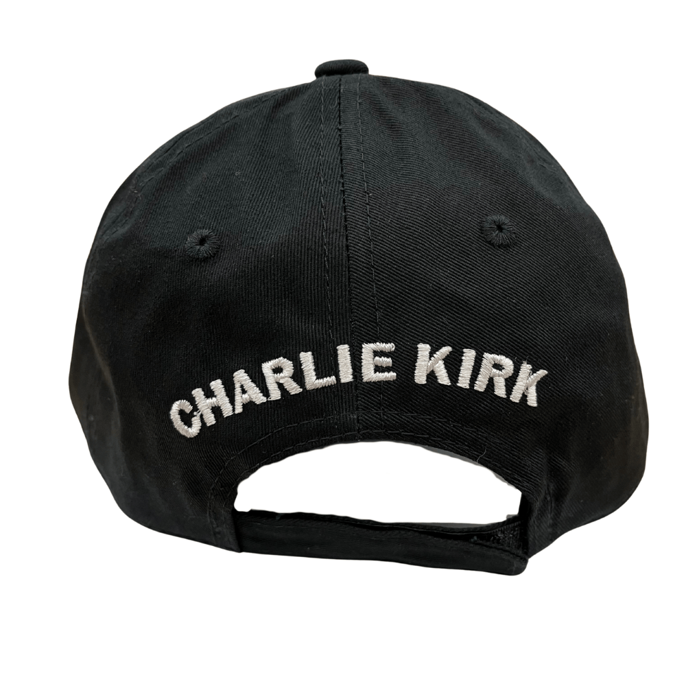 Charlie Kirk Freedom Black Hat featuring bold white 'FREEDOM' embroidery, displayed on a wooden table with a rustic background.