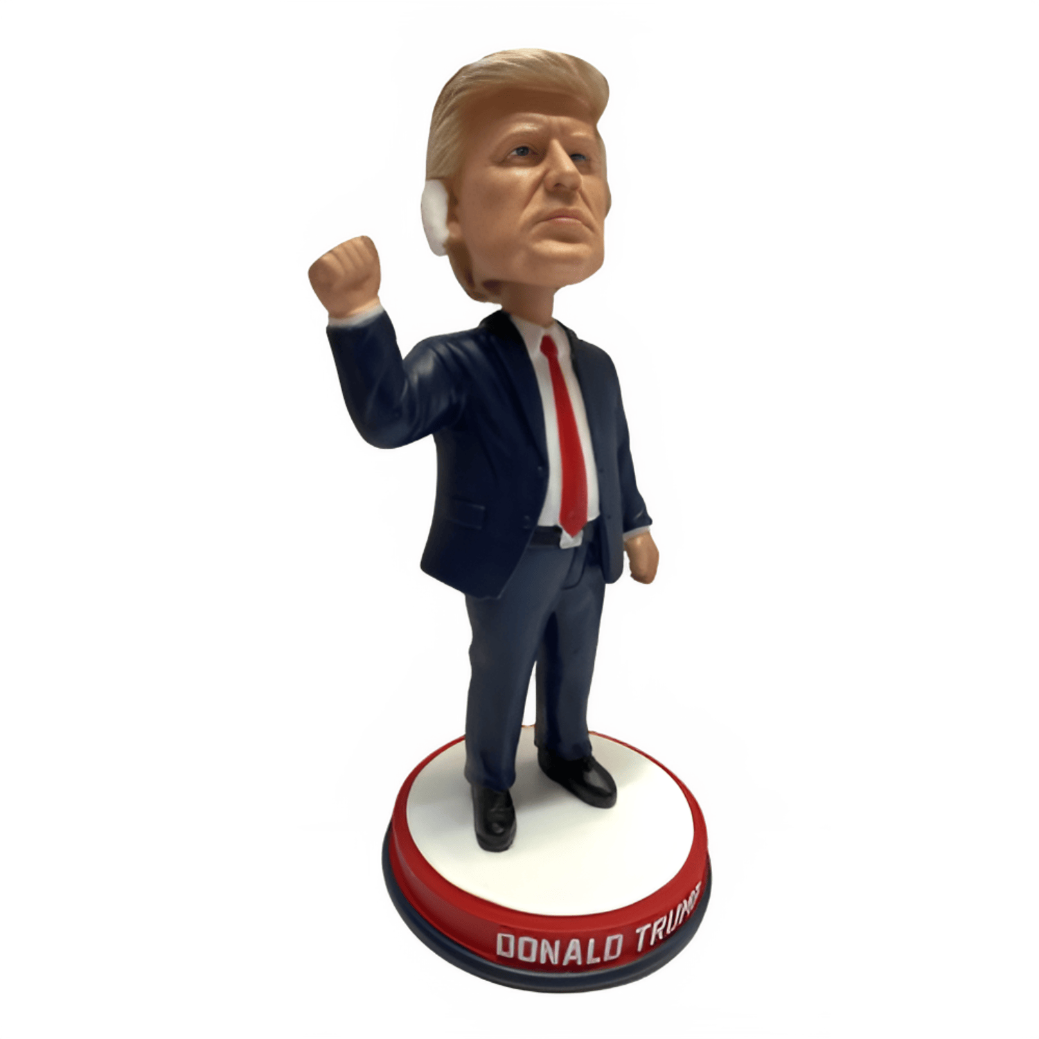 Trump Fist Pump Bandage Bobble Head featuring Donald Trump with a bloodied ear and a raised fist on a red, white, and blue base.