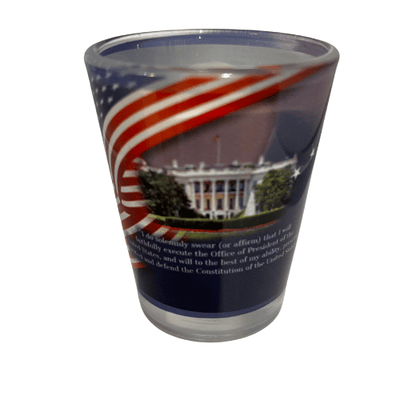 Donald Trump 47th President shot glass featuring his portrait and the White House design, beautifully displayed with a flowing American flag backdrop.