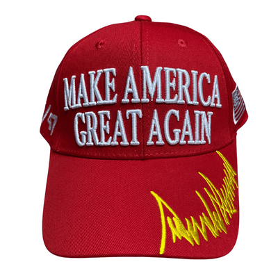 Red MAGA 45/47 Hat featuring bold white 'Make America Great Again' embroidery and gold Trump signature, displayed outdoors.