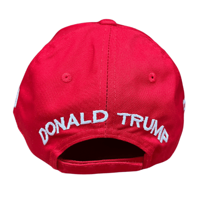 The Trump 2.0 Red Hat featuring bold white embroidery and American flag detail, worn in an outdoor setting to showcase patriotism.
