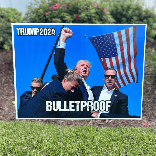 Trump 2024 Bulletproof Yard Sign featuring a vibrant image of Donald Trump with his fist raised high, displayed in a yard setting.