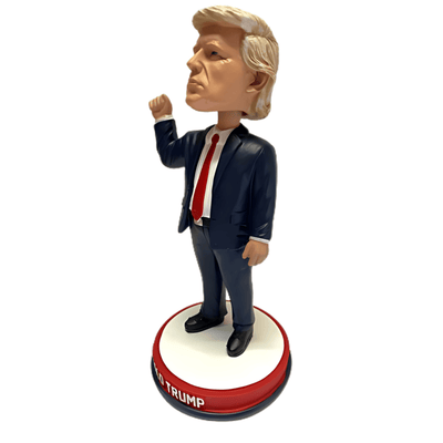Trump Fist Pump Bandage Bobble Head featuring Donald Trump with a bloodied ear and a raised fist on a red, white, and blue base.