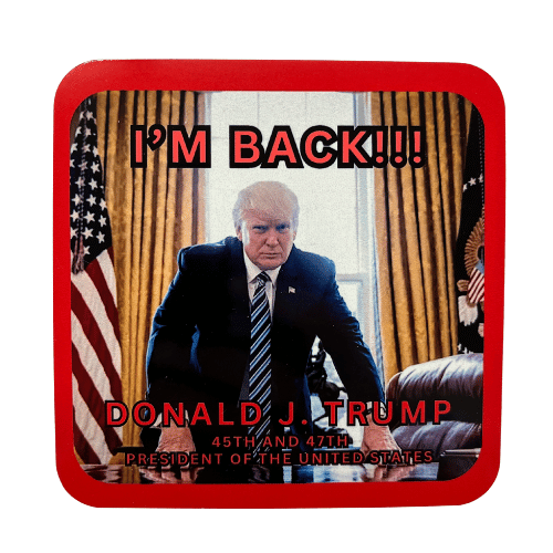 Trump Im Back Coaster featuring a bold image of Donald Trump at the Resolute Desk, surrounded by American flags, displayed on a wooden table.