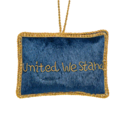 A felt ornament of the U.S. flag with gold stitching and “UNITED WE STAND” embroidered on the back — a simple, patriotic keepsake for holiday decor or year-round display.